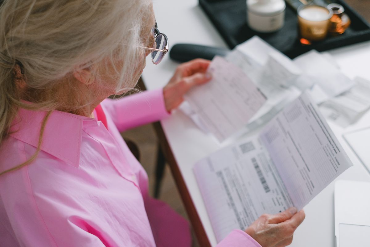 An older woman reviewing paperwork at a table.